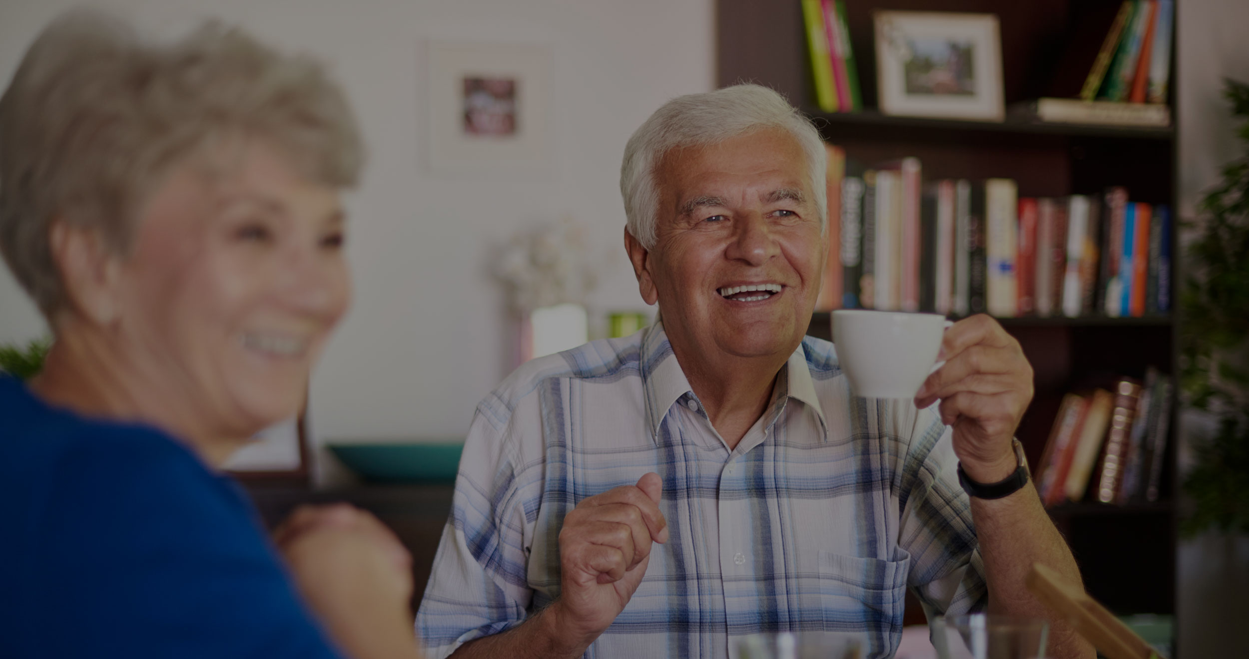 Elderly man laughing with coffee in his hand